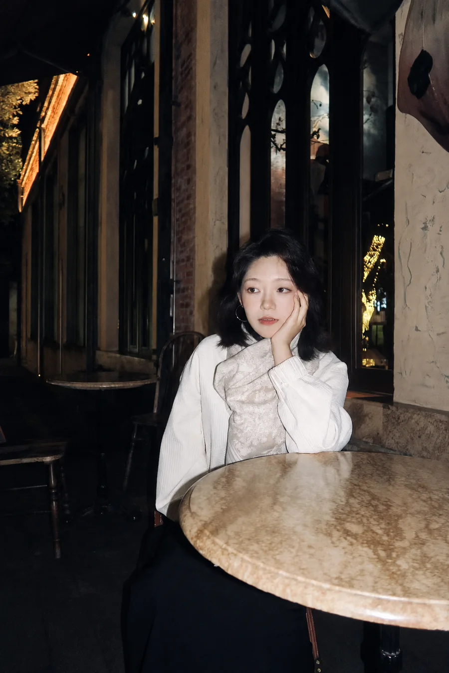王晶晶身穿白衣，坐在夜晚的咖啡馆里